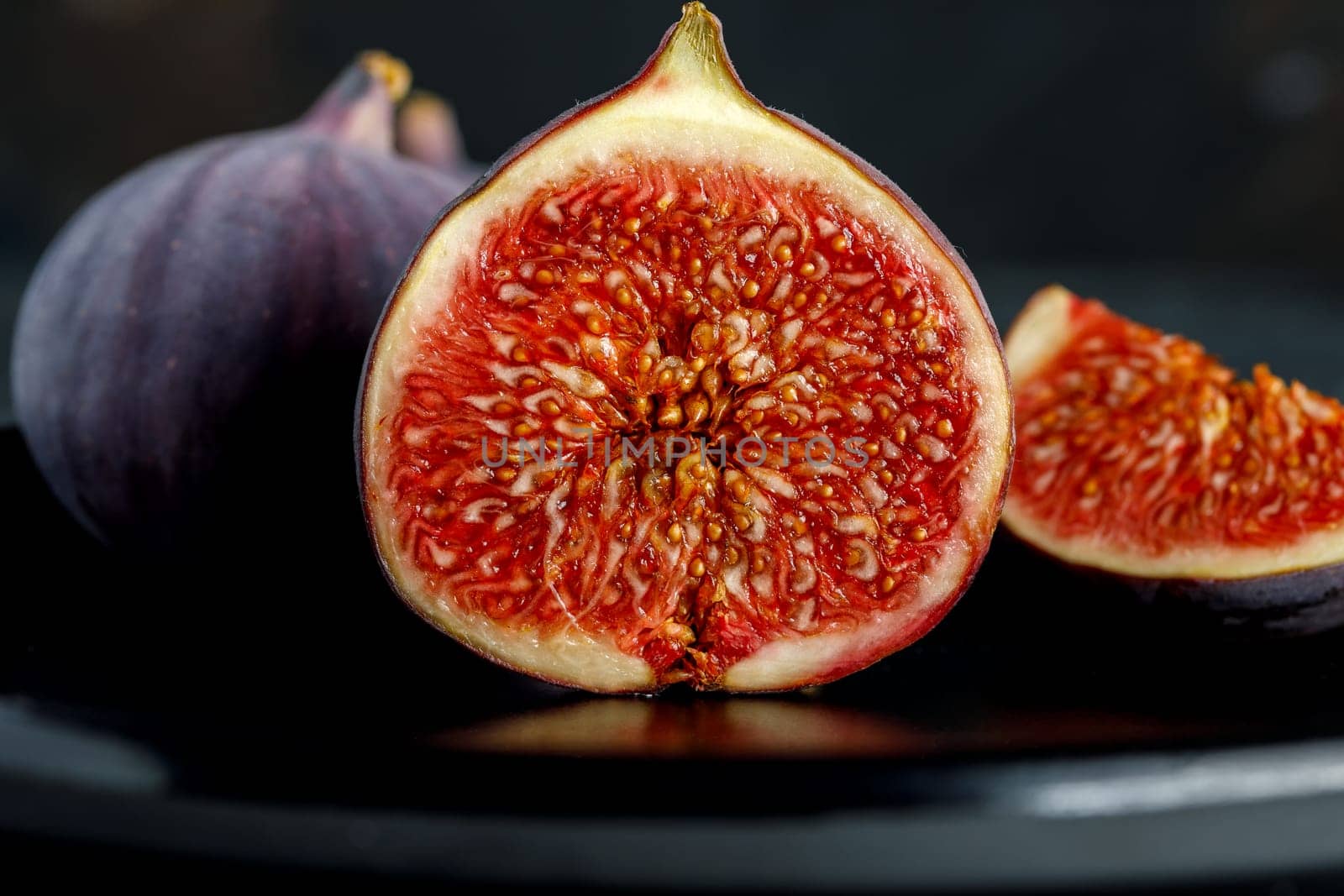 Tropical fig fruit, fresh in half section on the background of whole fruits and quarters