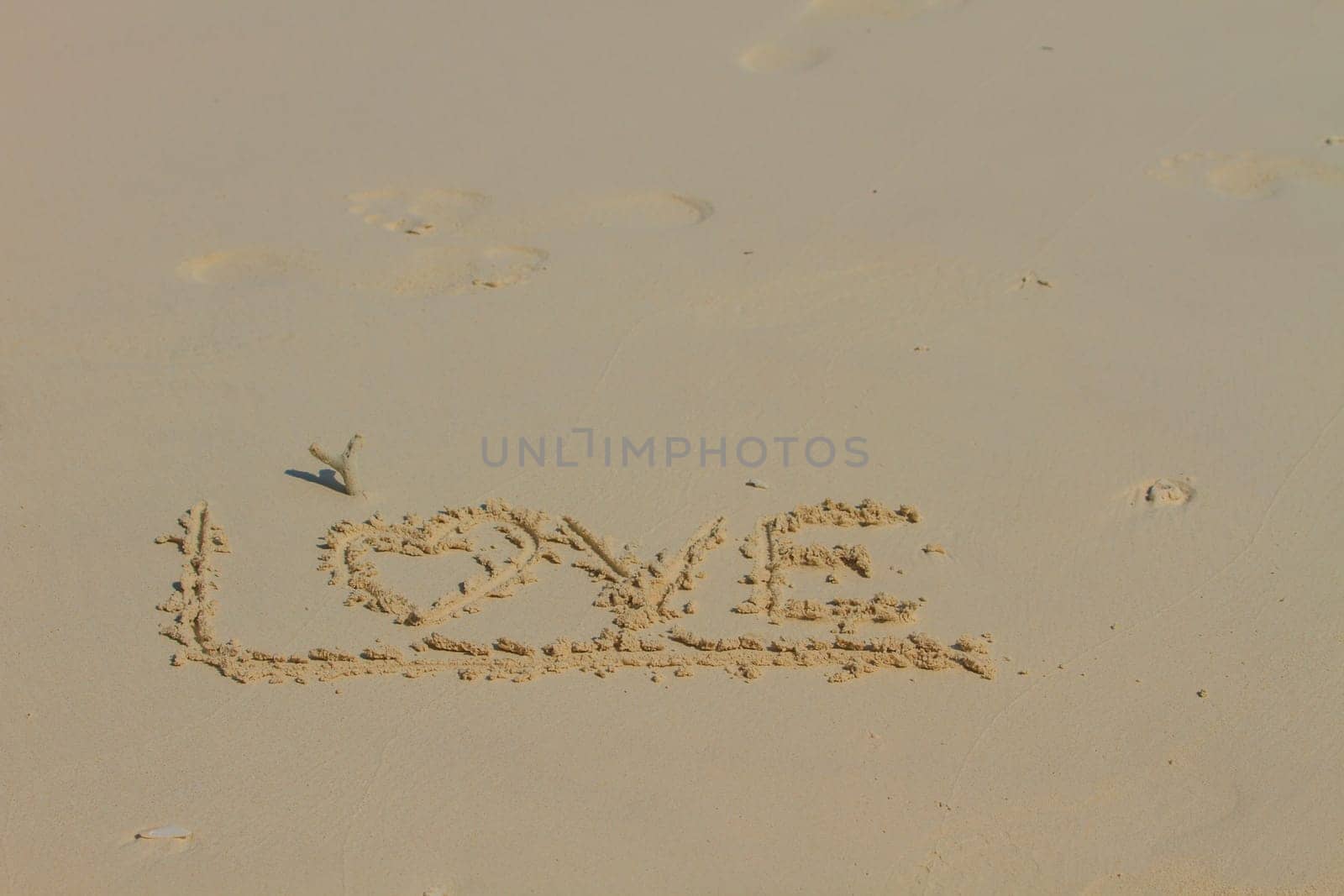 Word LOVE on sand, Drawing love word on beach