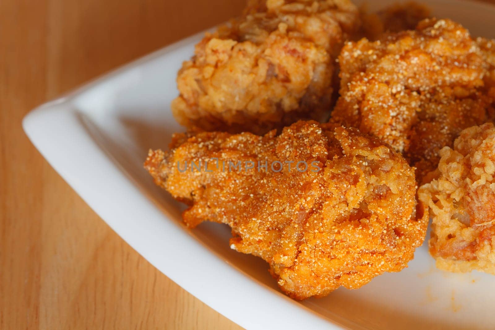 Fresh fried chicken on a white plate set on a wood table background