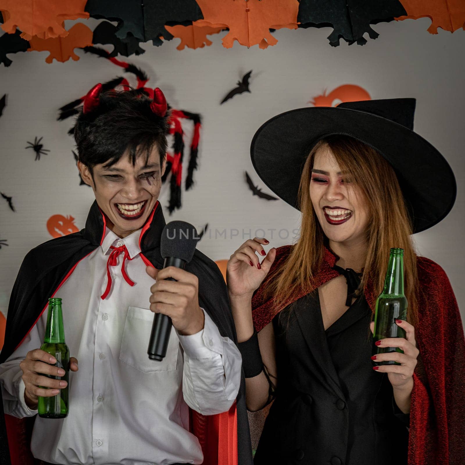 Group of young adult and teenager people celebrating a Halloween party carnival Festival in Halloween costumes drinking alcohol beer
