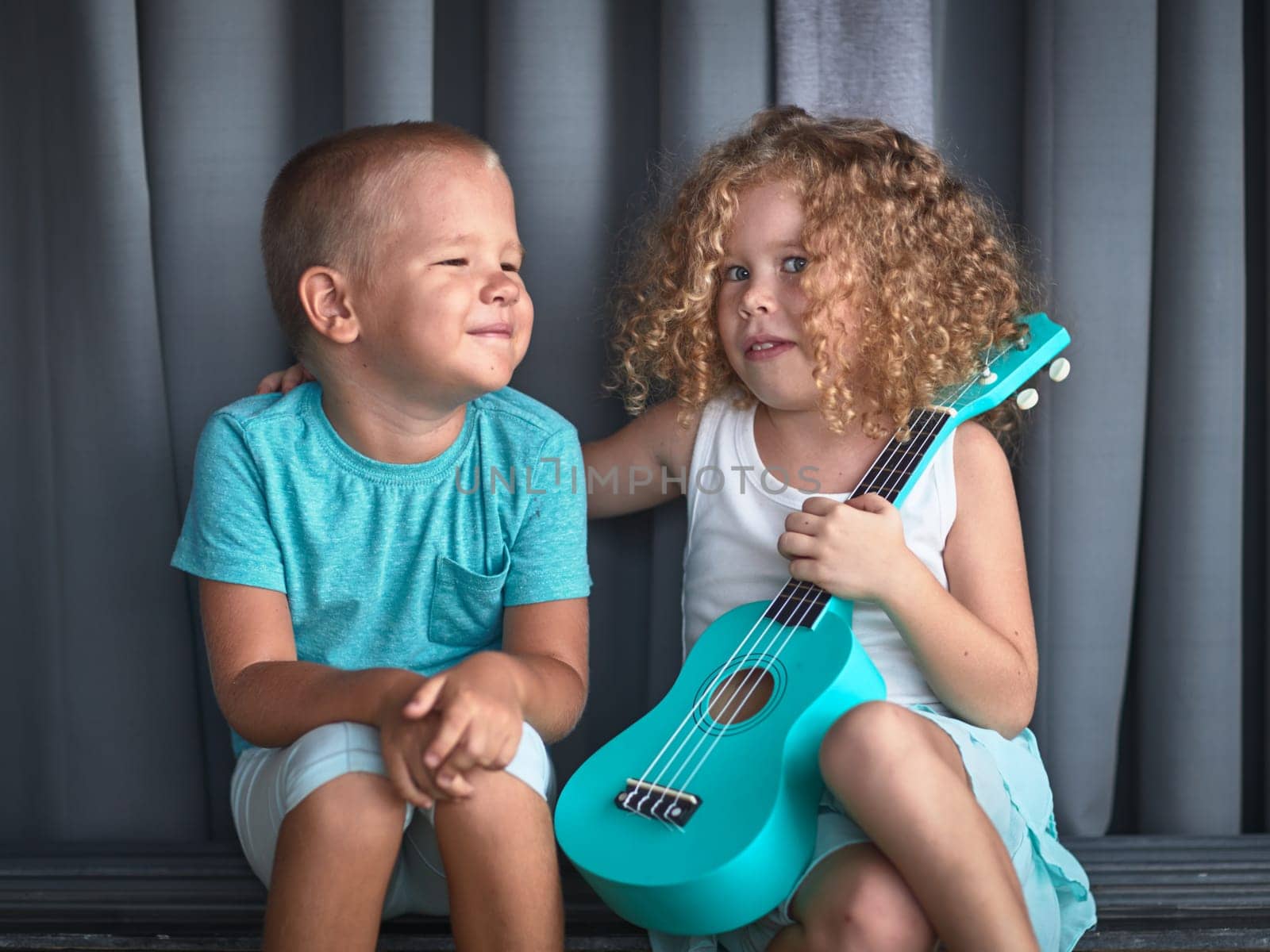 Portrait of a cute kids sitting ouddoor with ukulele