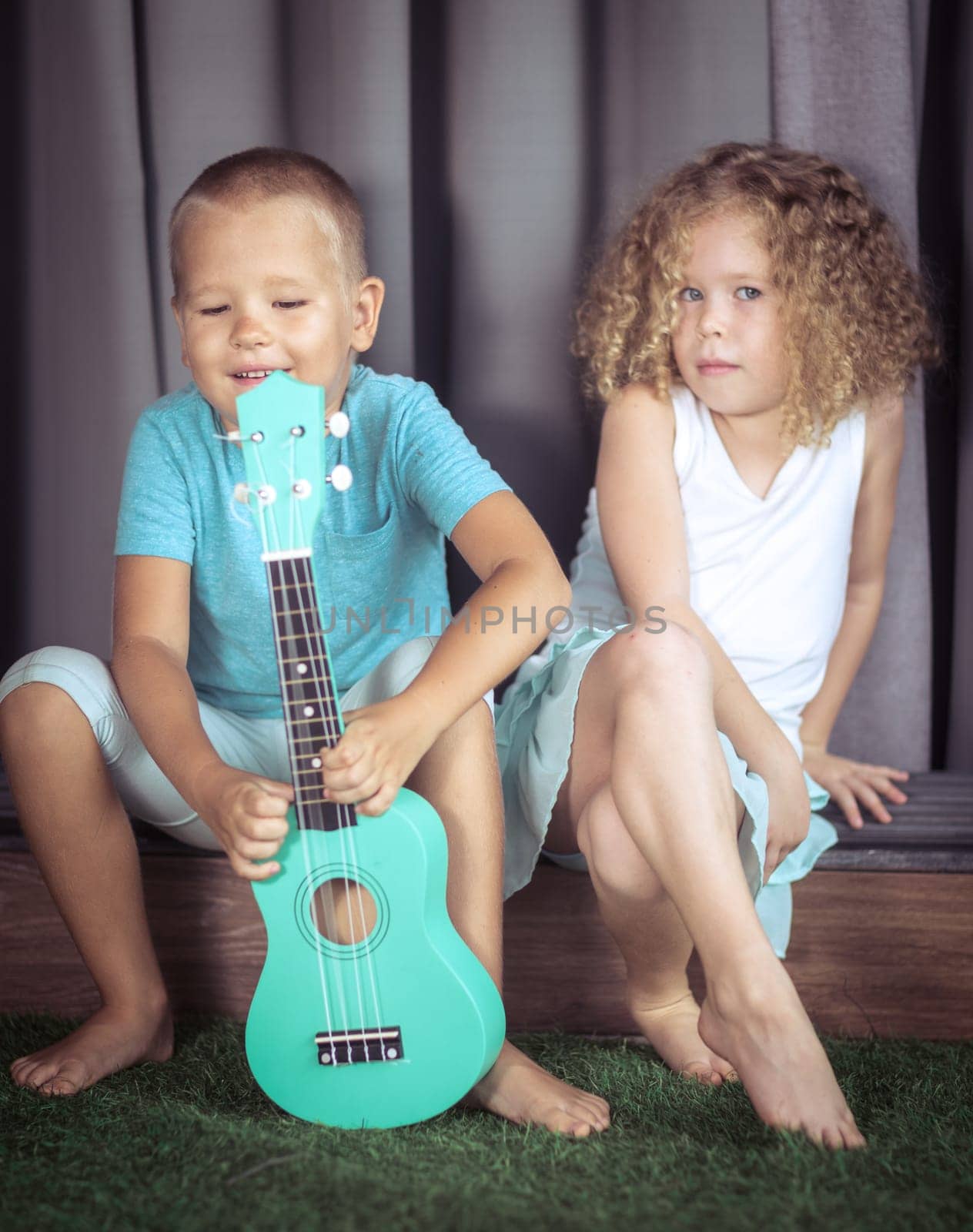 Portrait of a cute kids sitting ouddoor with ukulele