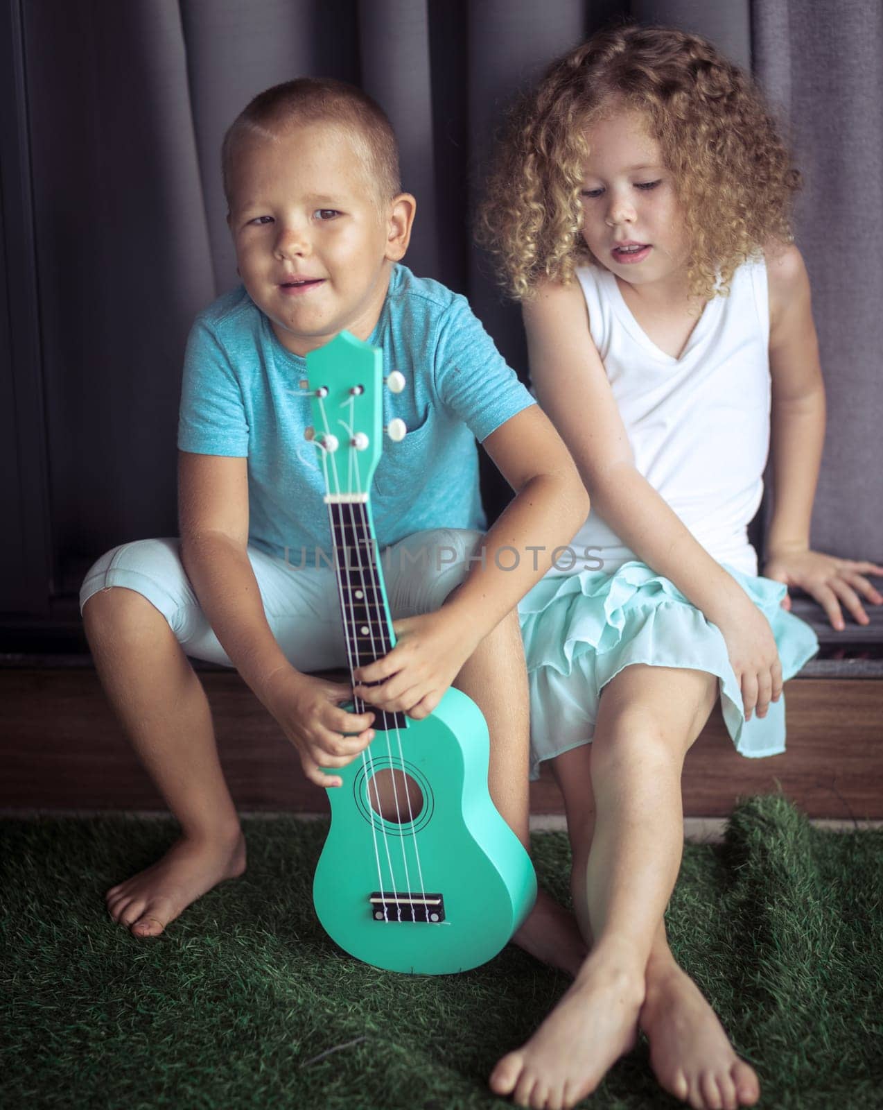 Portrait of a cute kids sitting ouddoor with ukulele