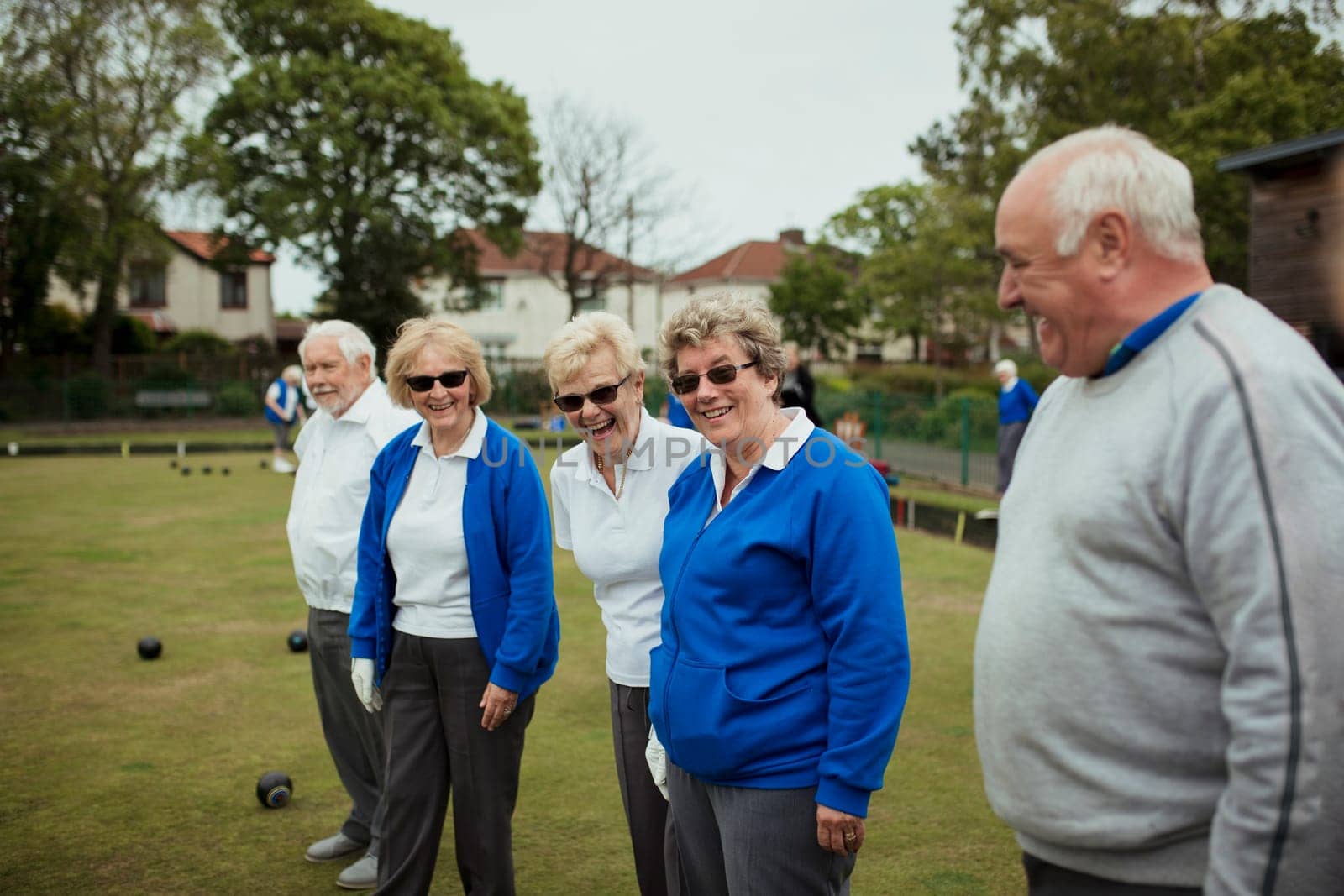 A side view shot of a group of seniors smiling in a bowling green.