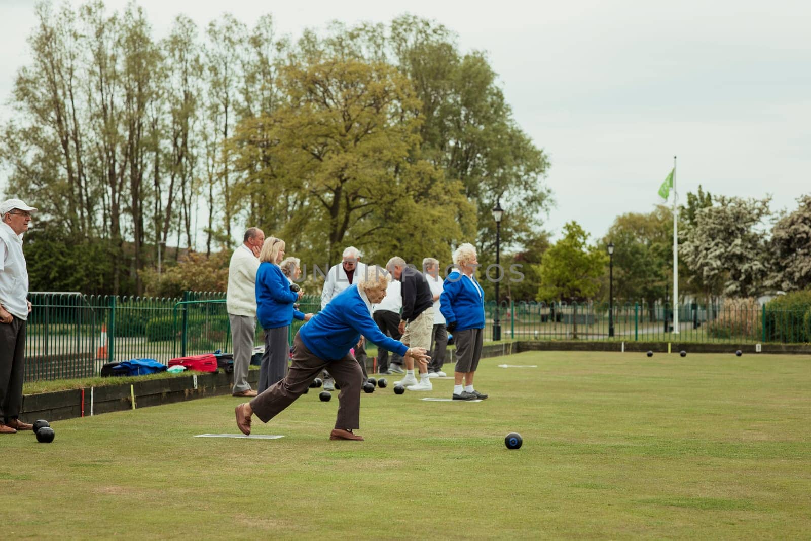A side view shot of a senior woman taking her shot in a game of lawn bowling.