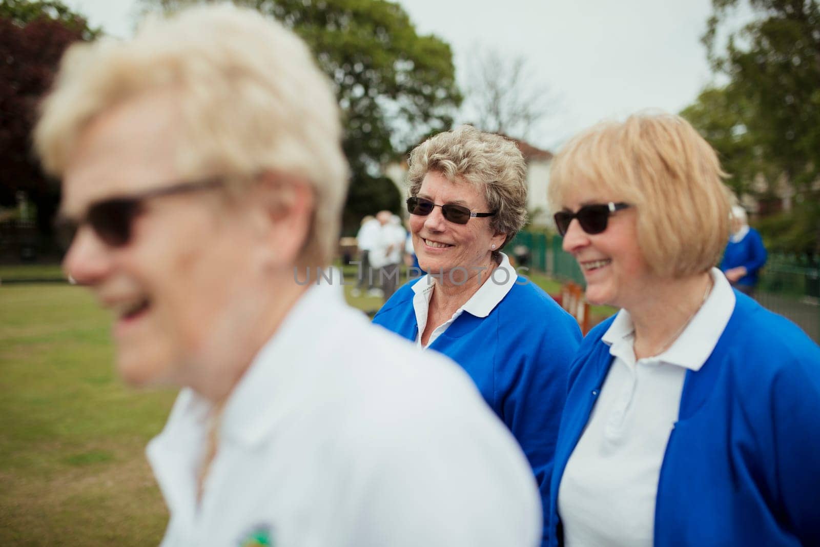 A side view shot of a group of senior women smiling at a bowling green.