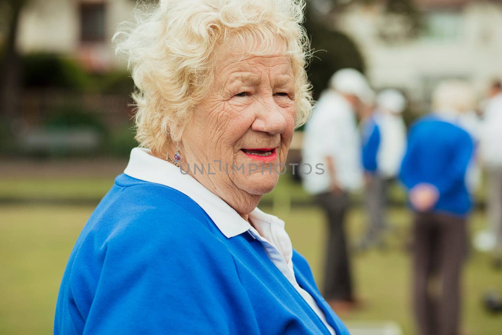 A close up shot of a senior woman smiling, looking away from the camera.