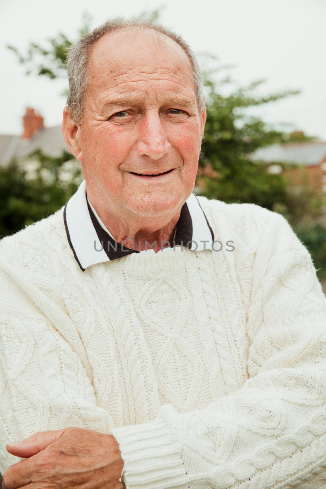 A portrait of a senior man smiling at a bowling green.