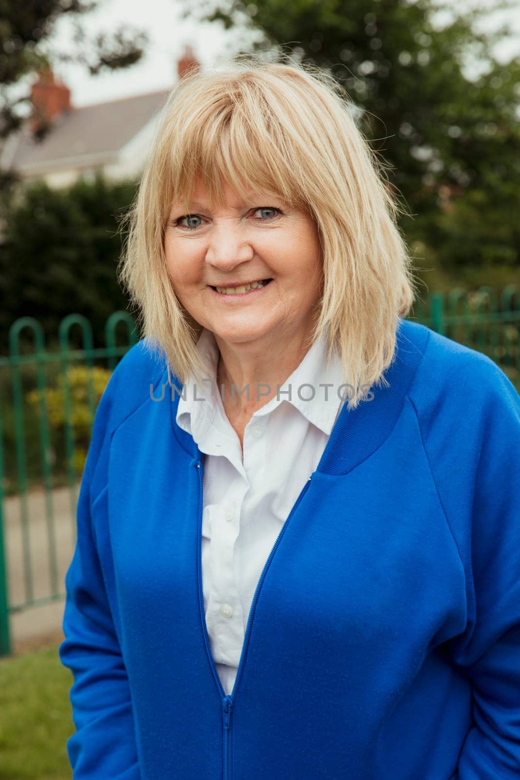 A portrait of a senior woman smiling at a bowling green.