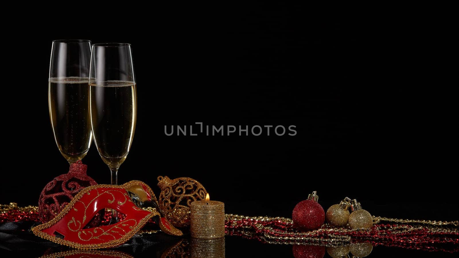 Two wineglasses with champagne and Christmas decorations on a black background. Copy space. New Year and Christmas