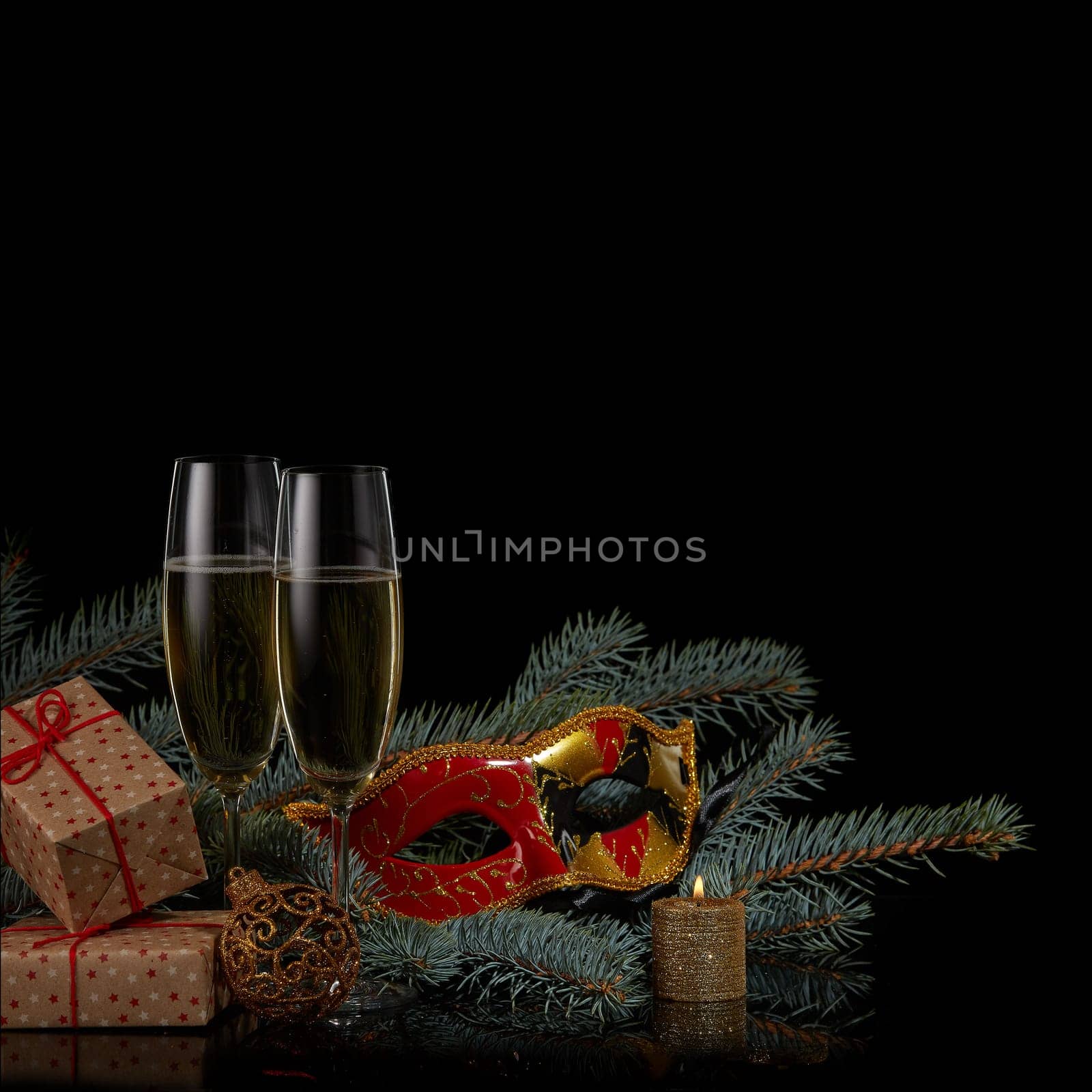 Still life with two wineglasses with champagne, gift boxes, fir tree branches and Christmas decorations on a black background. Copy space. New Year and Christmas