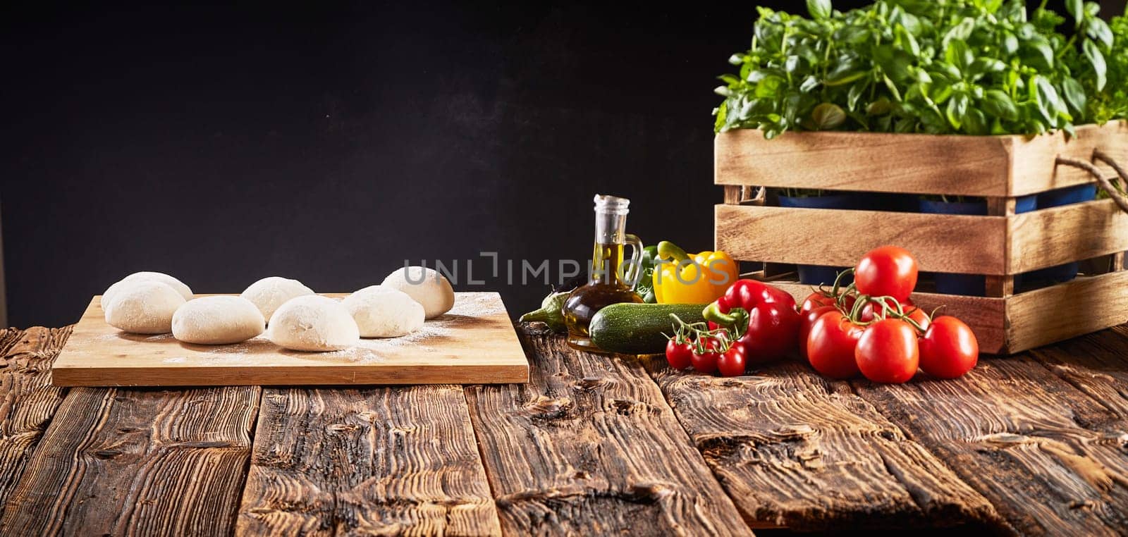 Fresh ingredients for Italian vegetarian pizzas with individual portions of raw dough on a tray, basil, tomatoes, sweet pepper, brinjal, and courgette in a panorama banner with copy space