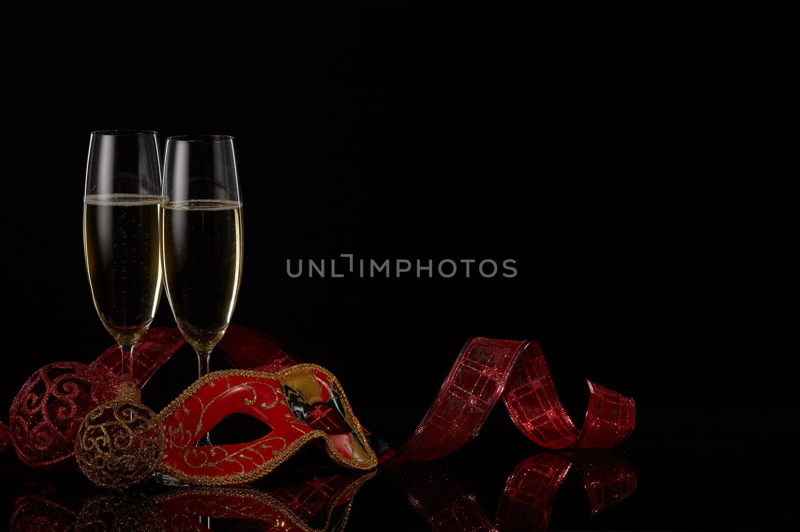 Two wineglasses with champagne and Christmas decorations on a black background. Copy space. New Year and Christmas