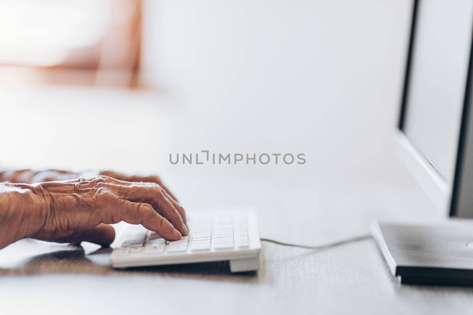 Elderly woman typing on a PC keyboard