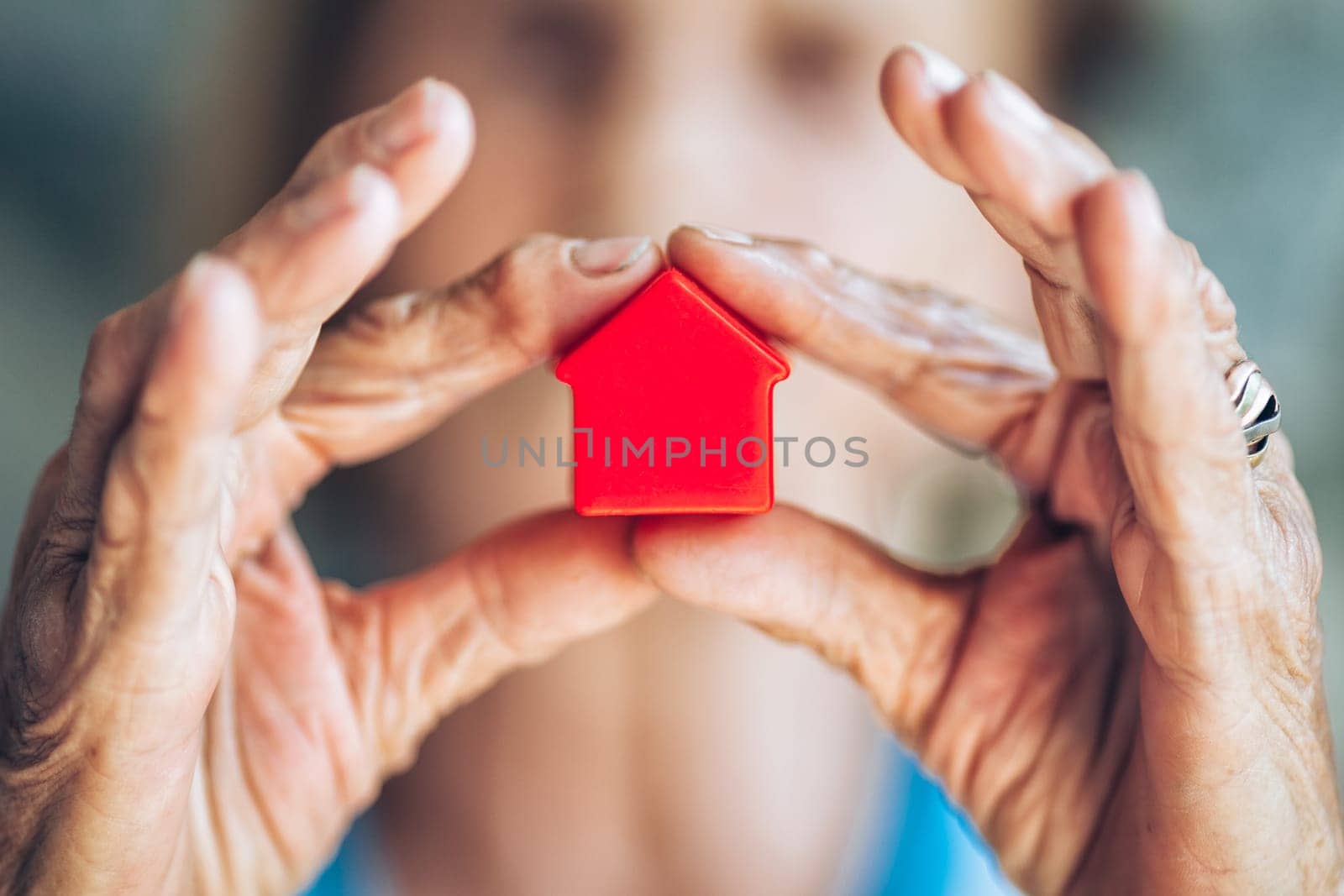 Elderly woman holding a small house in her hands
