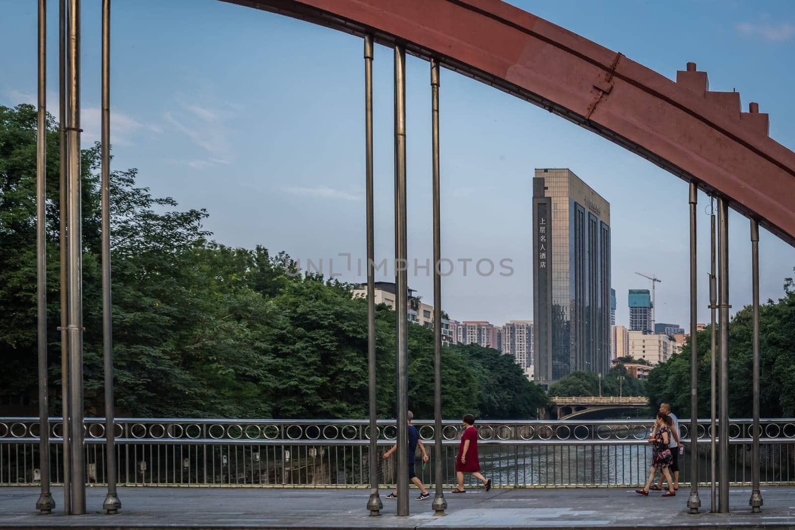 Chengdu, China - July  2019 : People walking across the arched steel bridge in Chengdu city, Sichuan Province