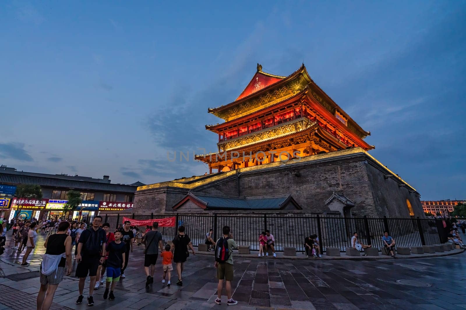 Xian, China -  July 2019 : Tourists walking in front of the Bell Drum Tower beautifully lit and illuminated at night, Shaaxi Province, Central China