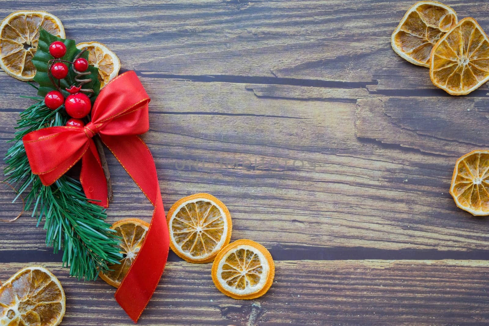 Christmas background from dried oranges, pine twig and red bow on a wooden table. Top view. Copyspace. Flatlay