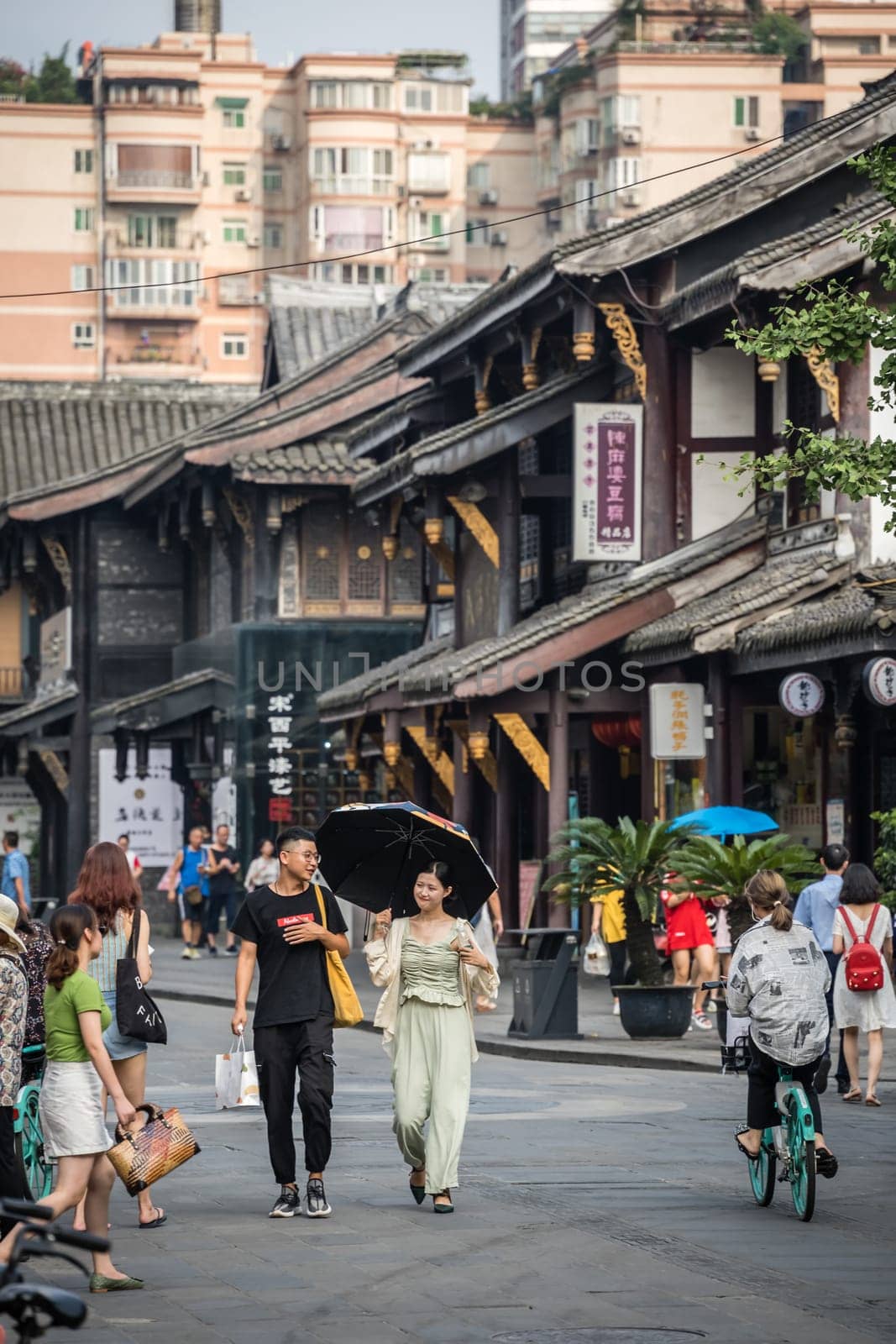 Chengdu, China -  July 2019 : Street scene in the city of Chengdu in summer, people walking on a street with old traditional chinese buildings in the background, Sichuan Province