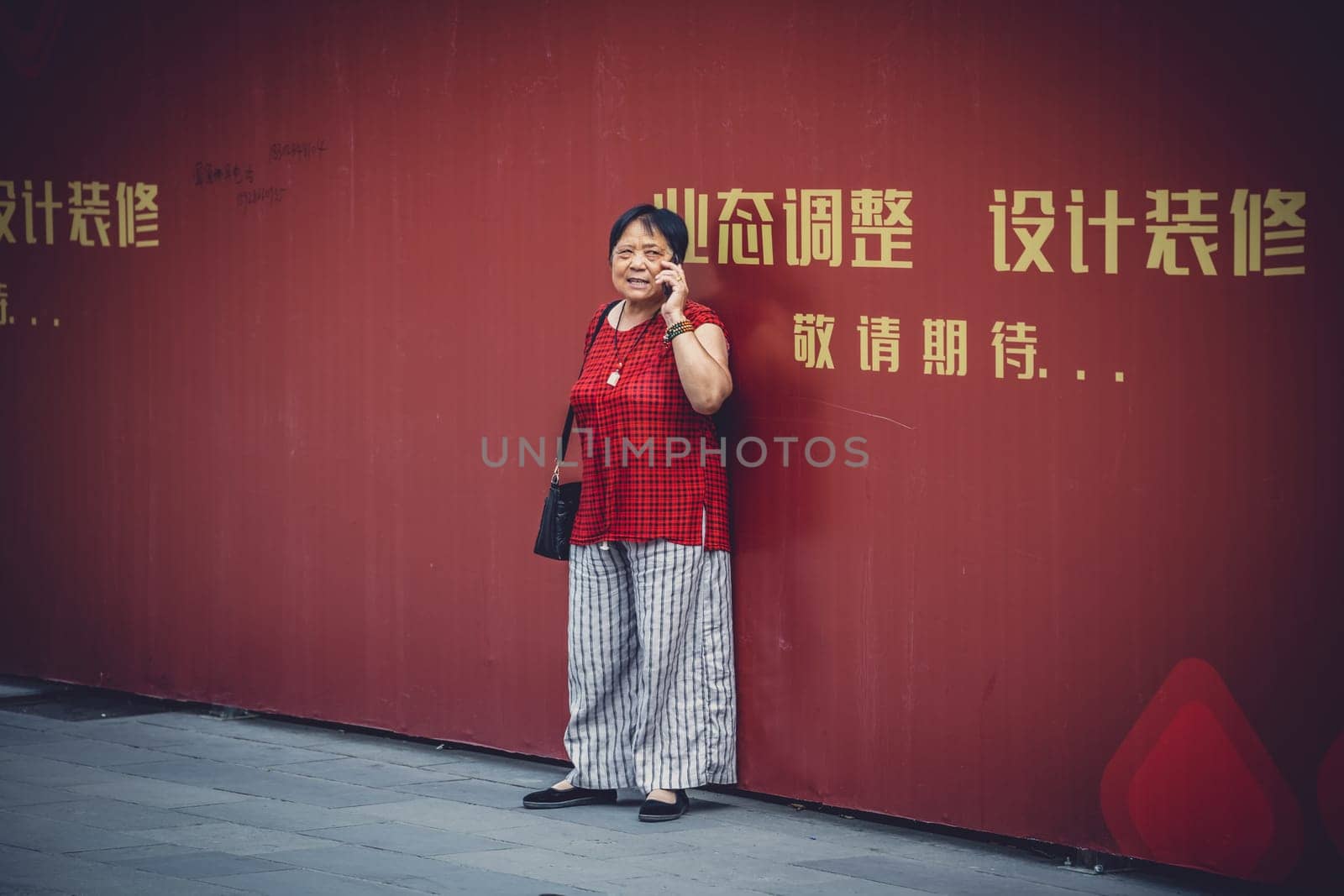 Chengdu, China -  July 2019 : Street scene in the city of Chengdu in summer, woman talking on her mobile phone, Sichuan Province