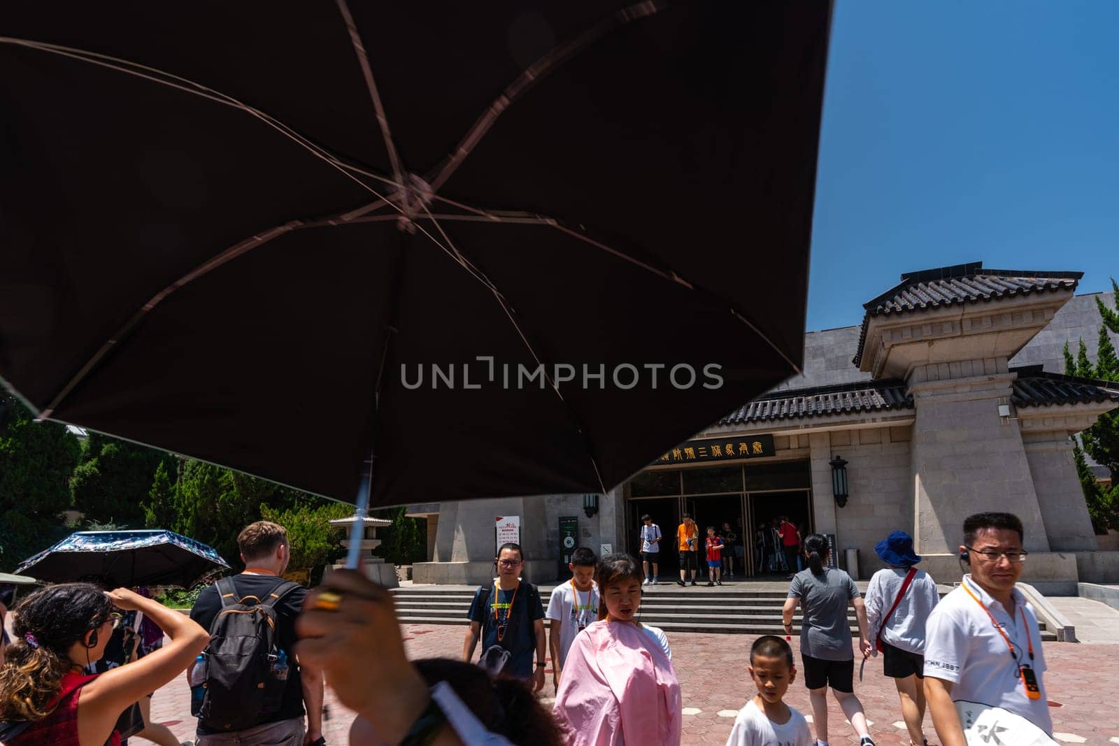 Xian, China -  July 2019 : Tourists walking on a path road leading to a museum site building containing Terracota Army sculptures, Xian, Shaanxi Province