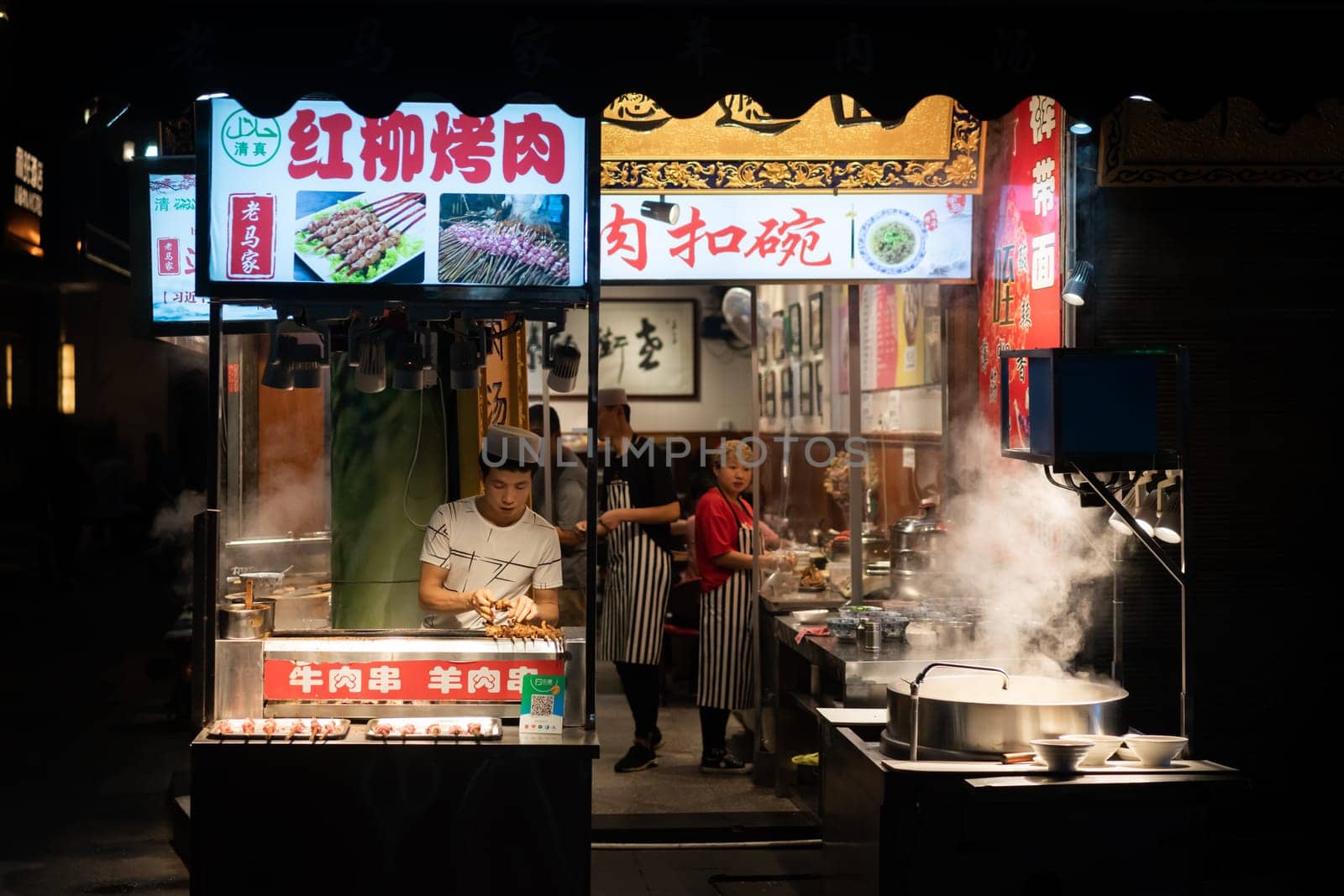 Xian, China -  August 2019 : Chef preparing hot food on a food stall operating at night on the street in the Muslim Quarter