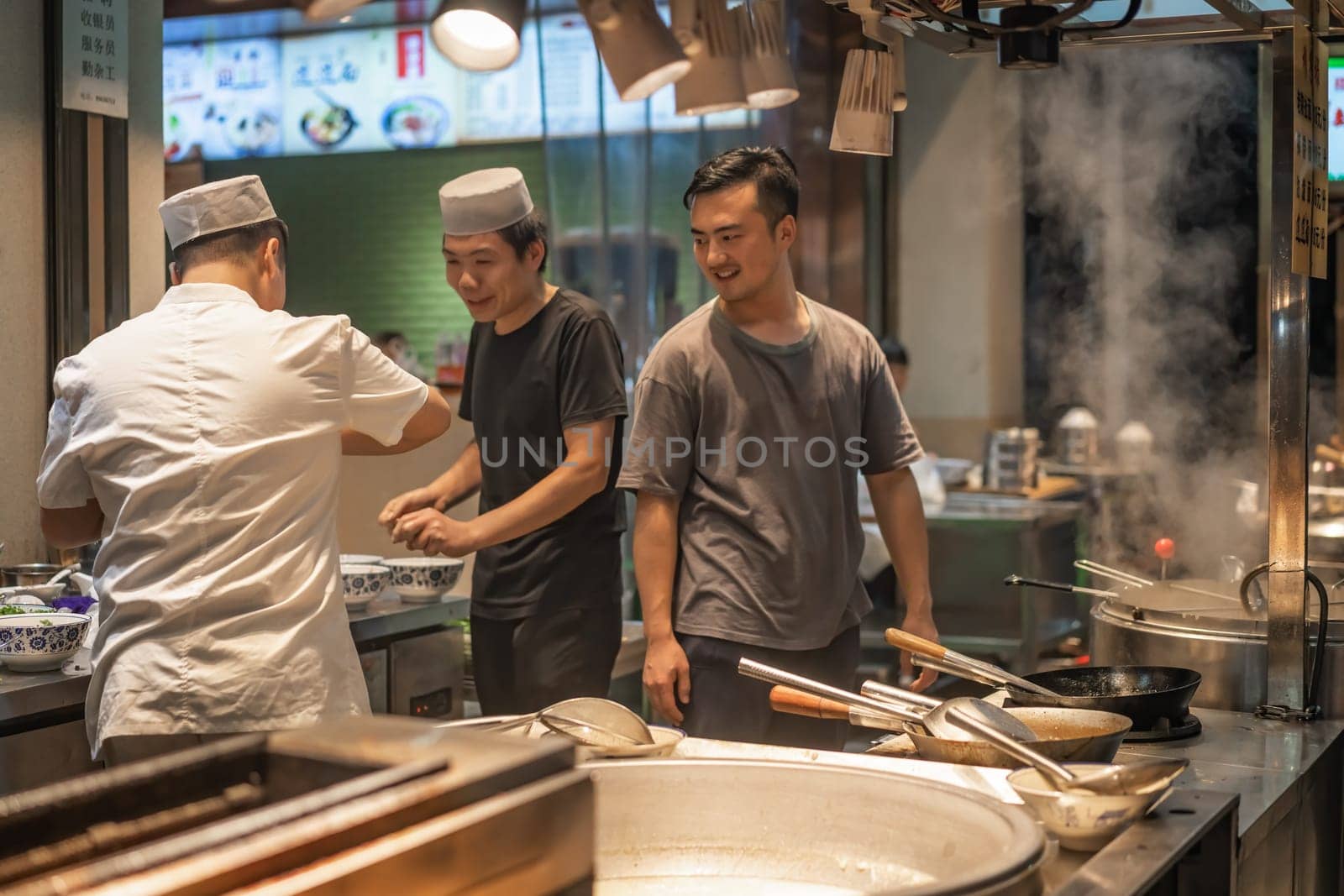 Xian, China -  August 2019 :  Chinese chefs playing around and having fun while not preparing food in a small restaurant on the street in the Muslim Quarter