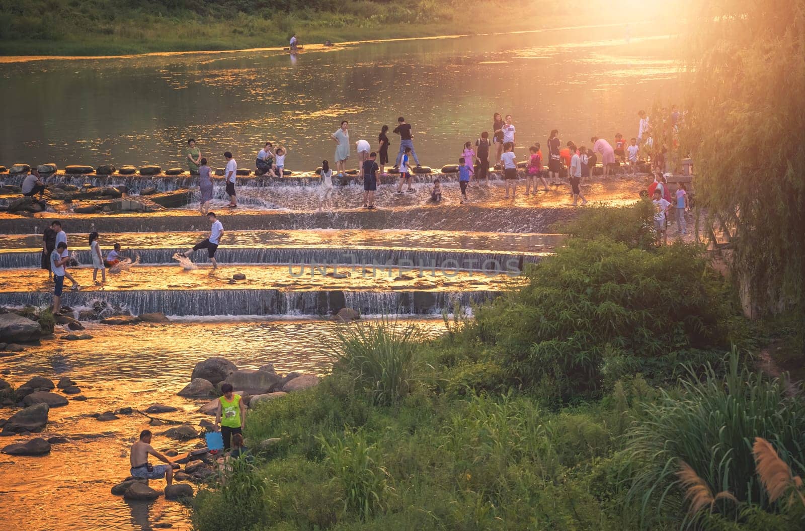 Wulingyuan, China -  August 2019 : People crossing the river during stormy sunset near Xibu Street, located near the ruins of the ancient city of Tujia