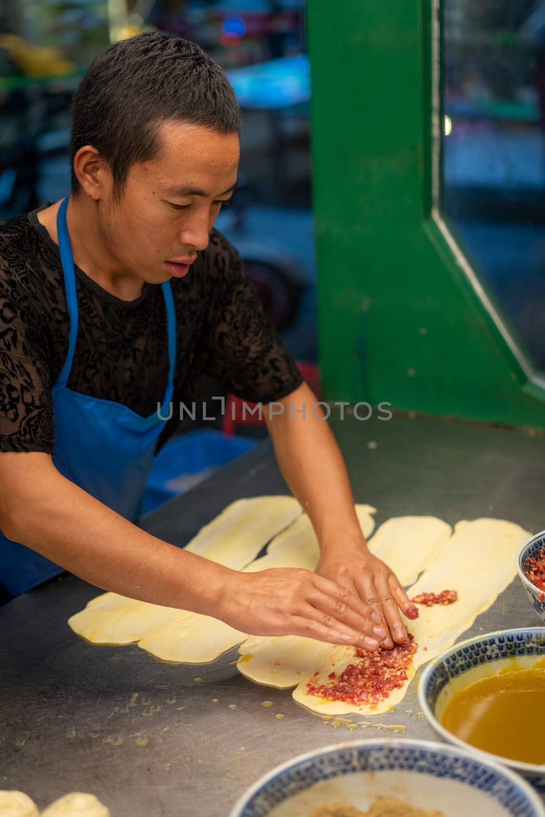 Xian, China -  August 2019 :  Man making minced beef meat filled pastries in a small local bakery on the street in Muslim Quarter, Xian town