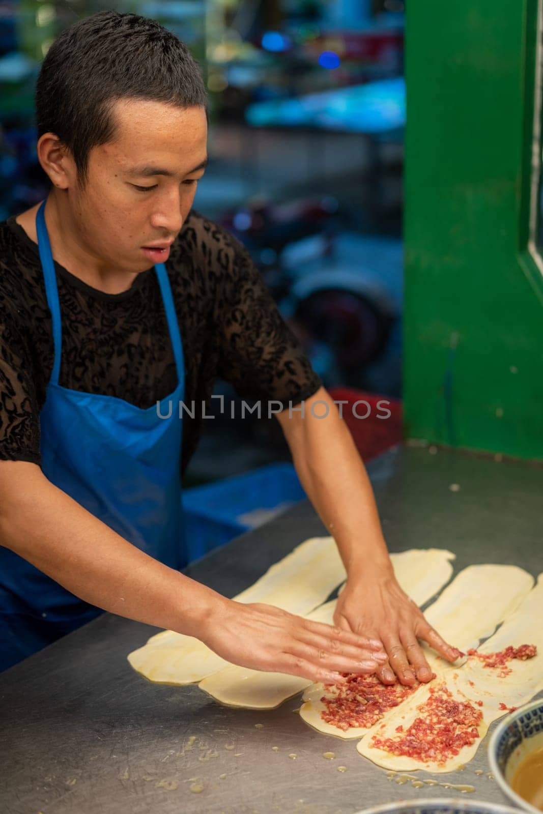 Xian, China -  August 2019 :  Man making minced beef meat filled pastries in a small local bakery on the street in Muslim Quarter, Xian town
