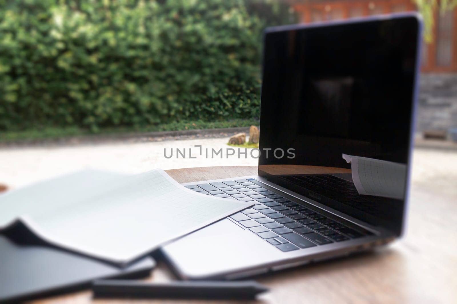 Modern laptop computer on wooden table in home garden, stock photo