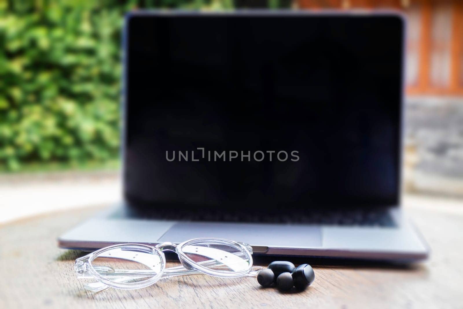 Modern laptop computer on wooden table in home garden, stock photo