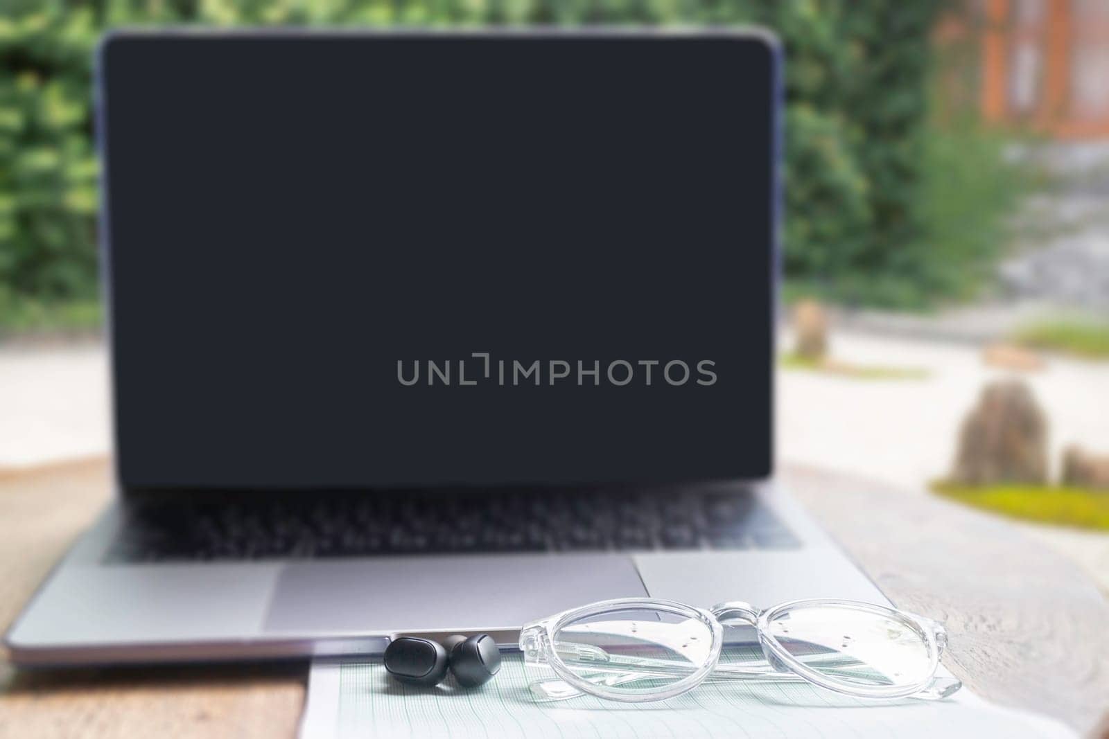 Modern laptop computer on wooden table in home garden, stock photo