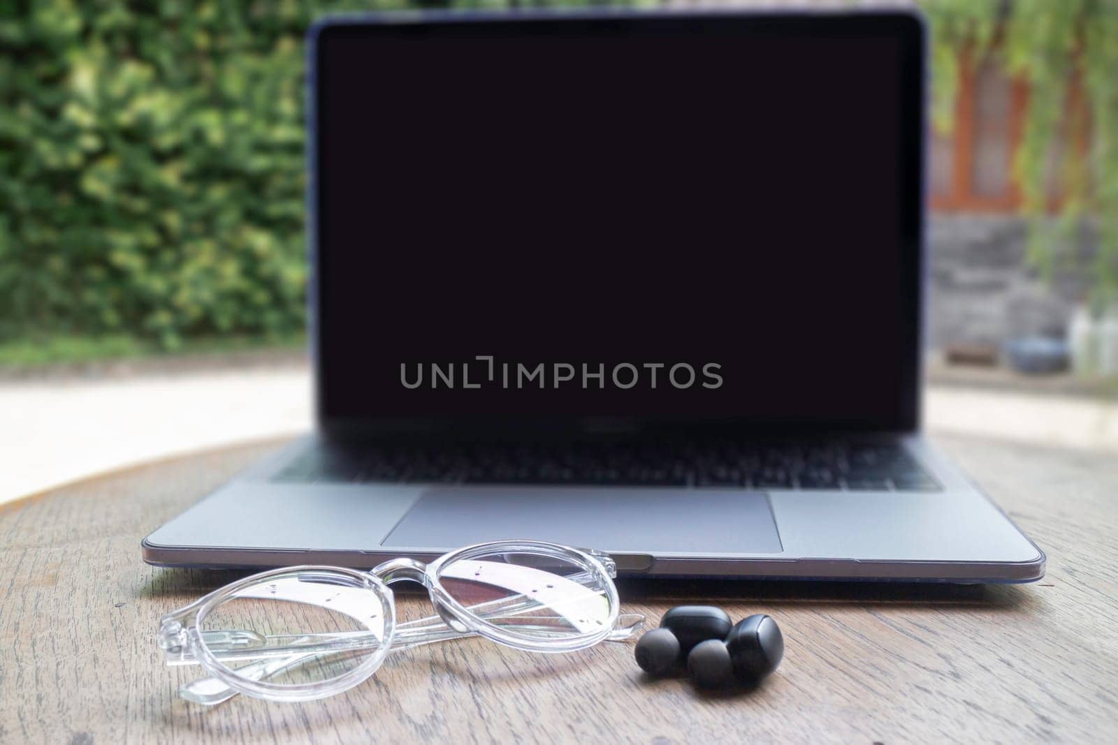 Modern laptop computer on wooden table in home garden, stock photo