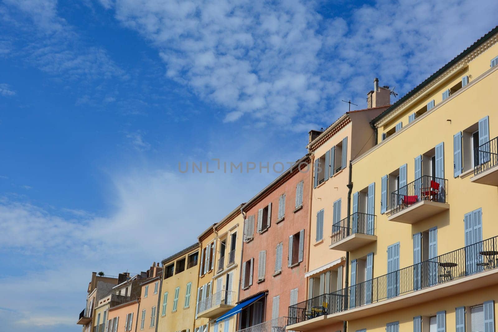 Colored house facade in the historic center of Saint Tropez, France, with balconies and many  blue sky and copy space