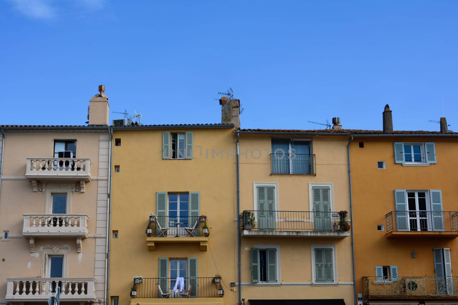 Colored house facade in the historic center of Saint Tropez, France, with balconies and blue sky