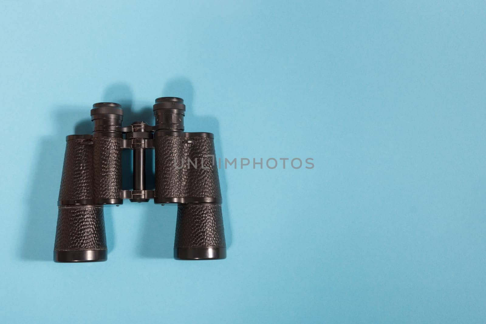 Black metalic binoculars on a blue background