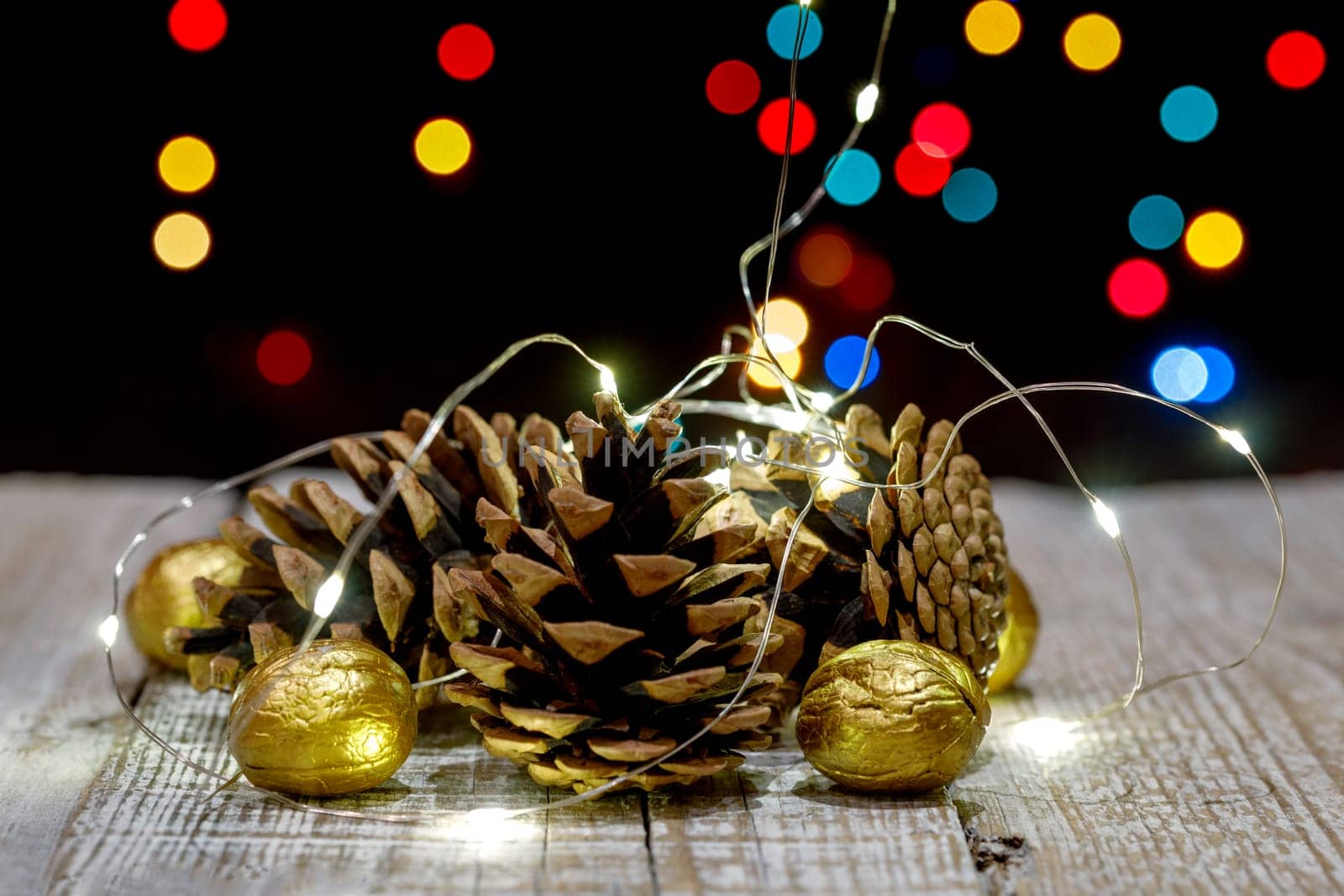 Composition of cones and painted walnuts with a garland of lpmpots and bokeh in the background