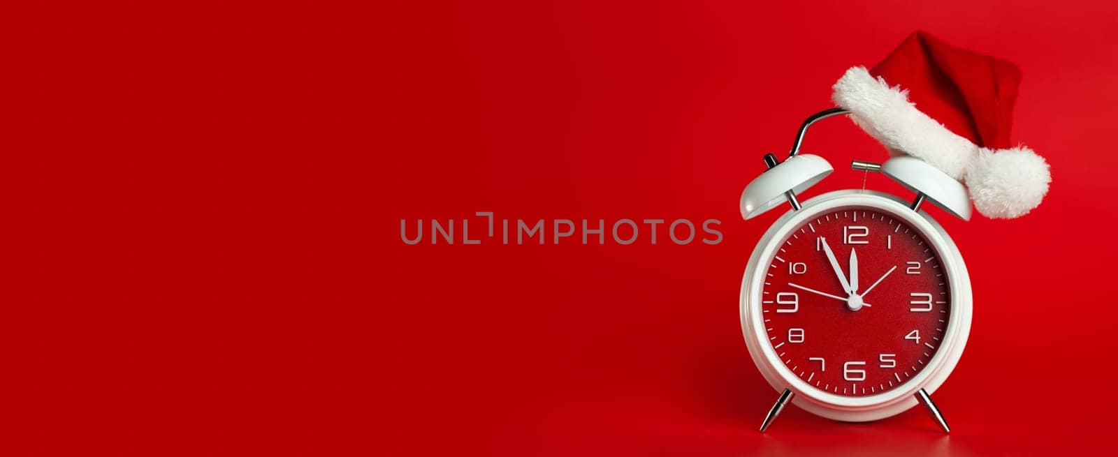 Red clock with Christmas Santa hat. Time for Christmas shopping concept. Blank red space for text.