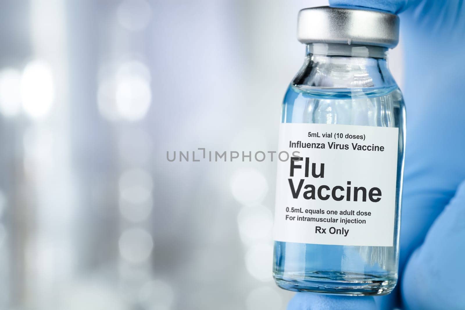 Healthcare concept with a hand in blue medical gloves holding Flu, Influenza, vaccine vial