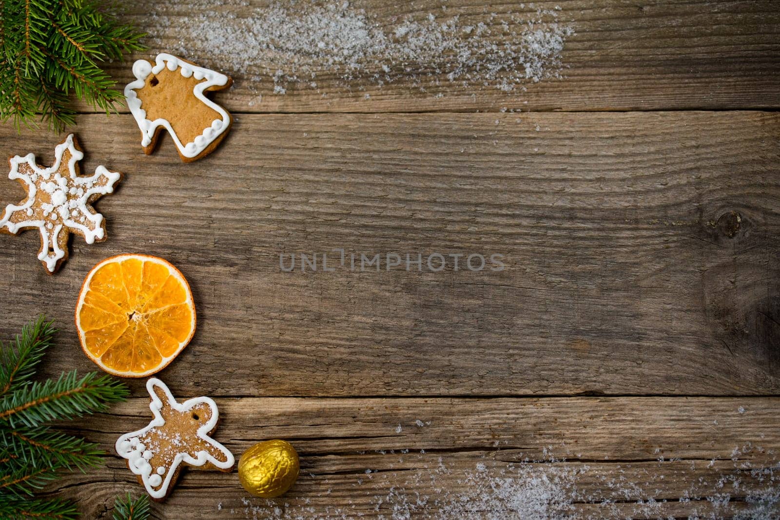Christmas background from wooden old boards with a place for copy space, cookies in the shape of angels and snowflakes, an orange slice, a golden nut and blue fir