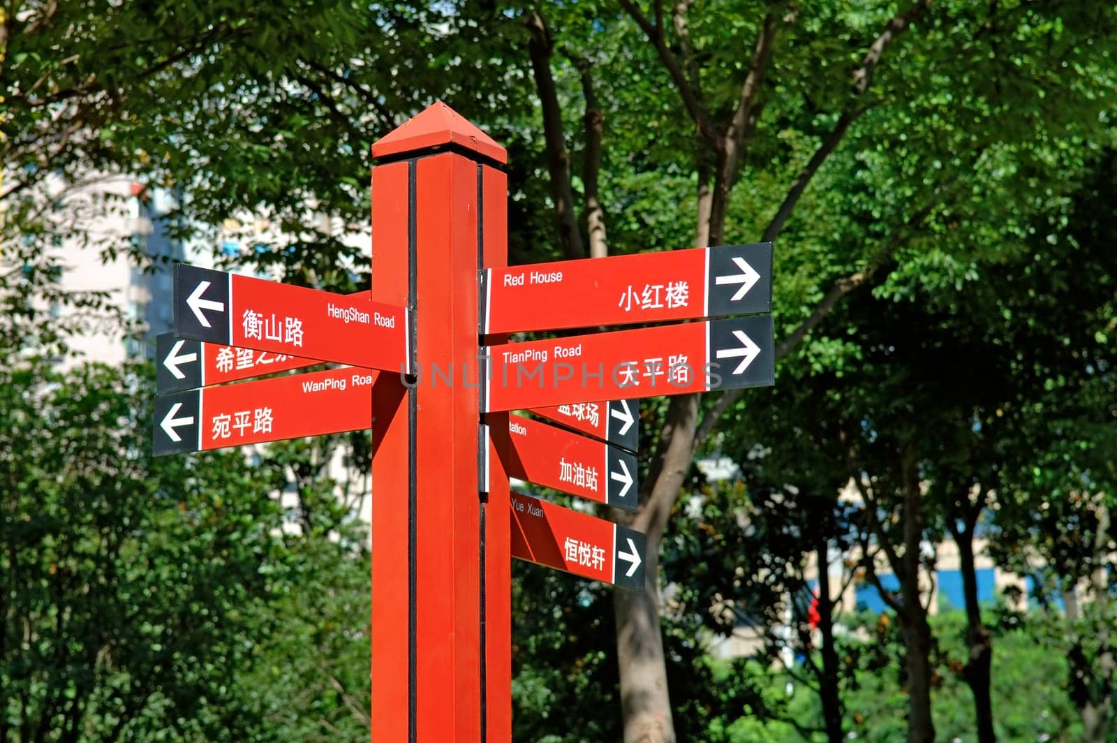 Multiple way red signpost in city park