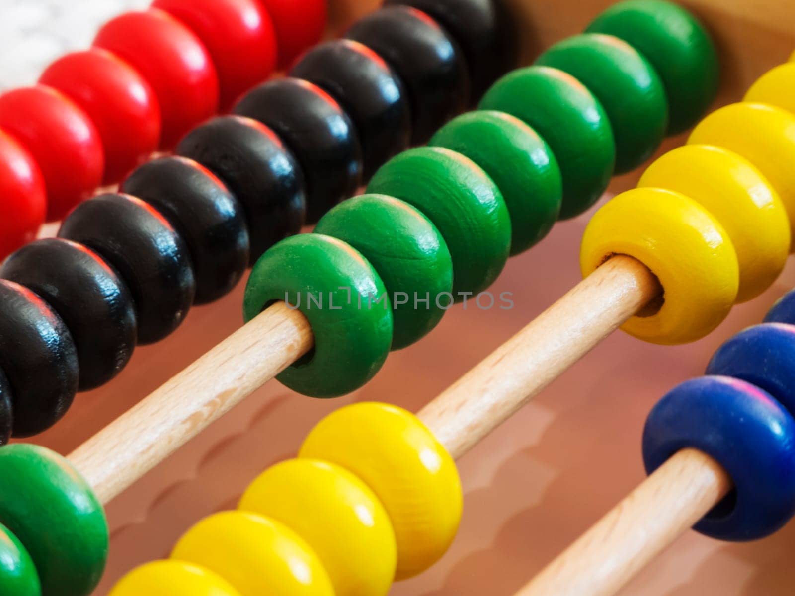 Close-up of a wooden abacus with colorful quills in an oblique view.