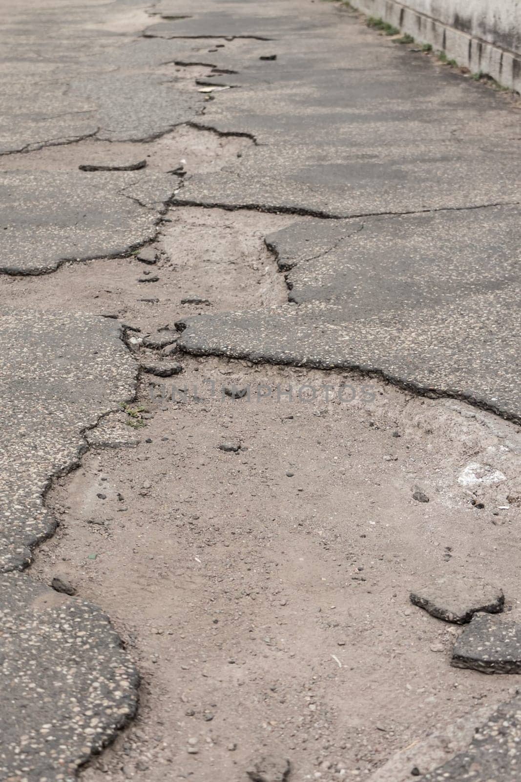Neglected street with potholes damage shows accident traffic risk through holes in asphalt due poverty or investment maintenance jam.