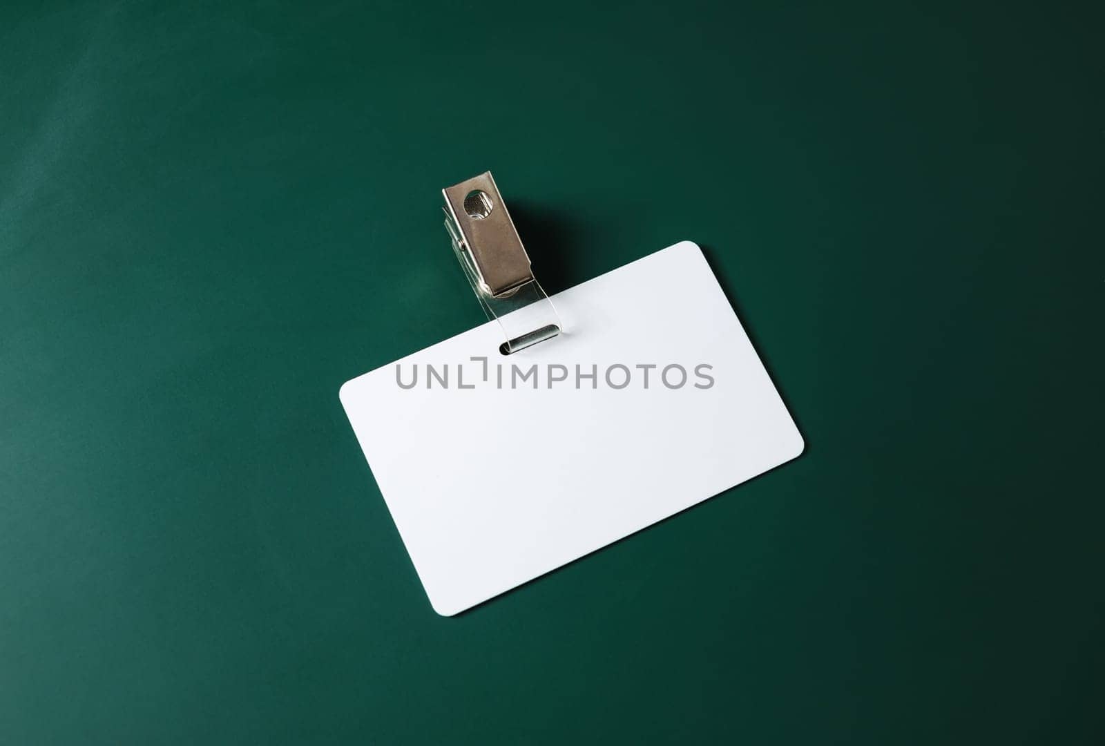 Blank ID card. White plastic badge on green blackboard background. Copy space for text. Responsive design template.