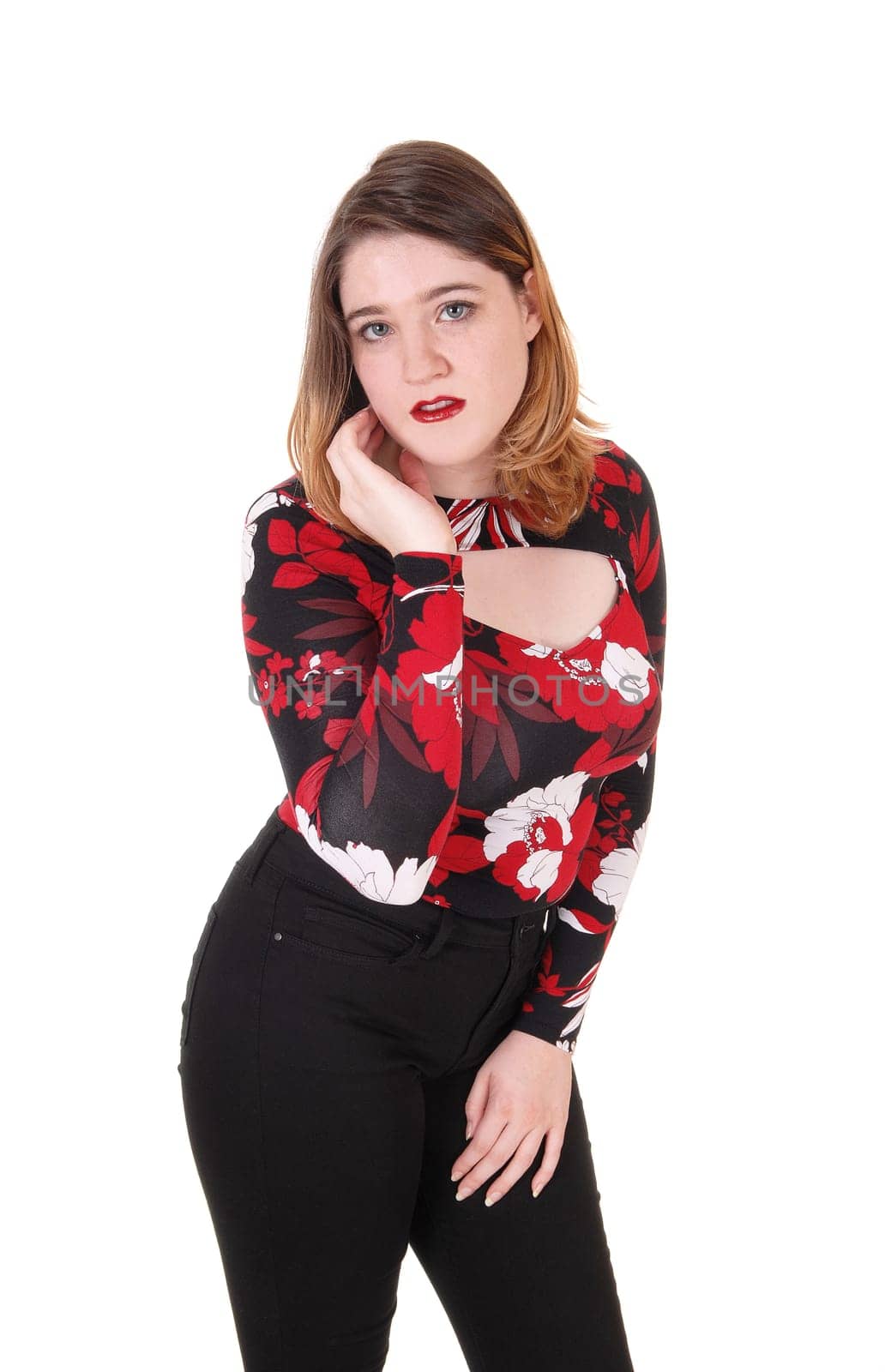 A young sad looking woman standing in black tights and colorful.blouse with one hand on her face, isolated for white background.