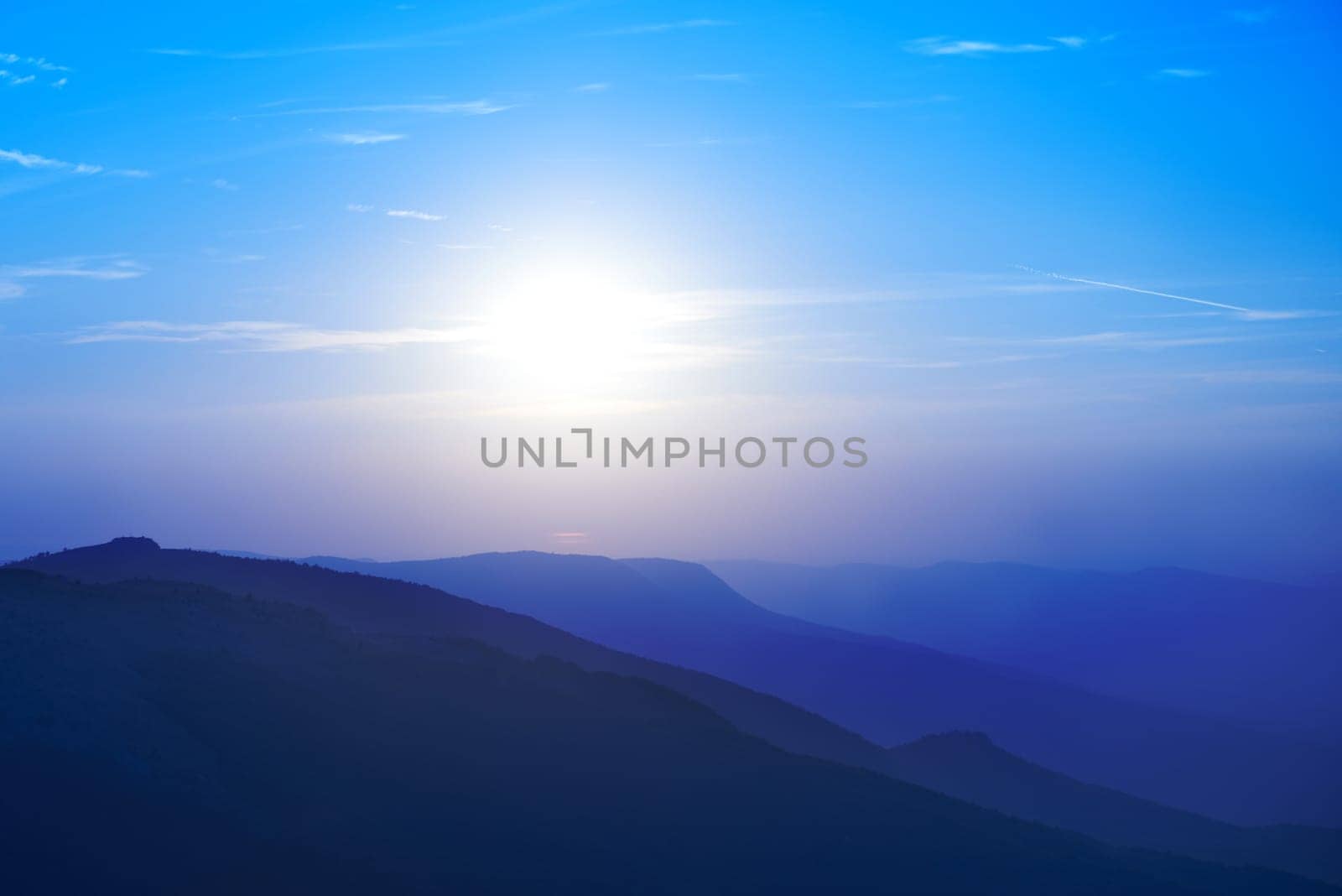 Beautiful sunset at the mountains. Colorful landscape with sun and blue sky