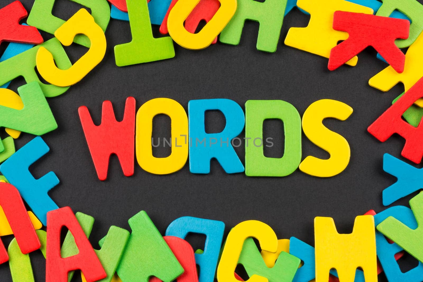 The "WORDS"" text from colorful letters around colorful letters on dark background, english language concept."
