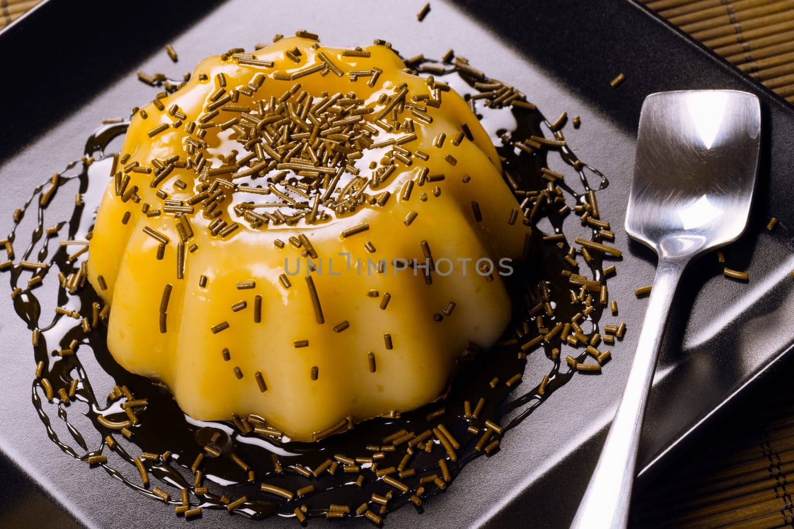 Banana pudding sweet dessert is on black square plate on table.