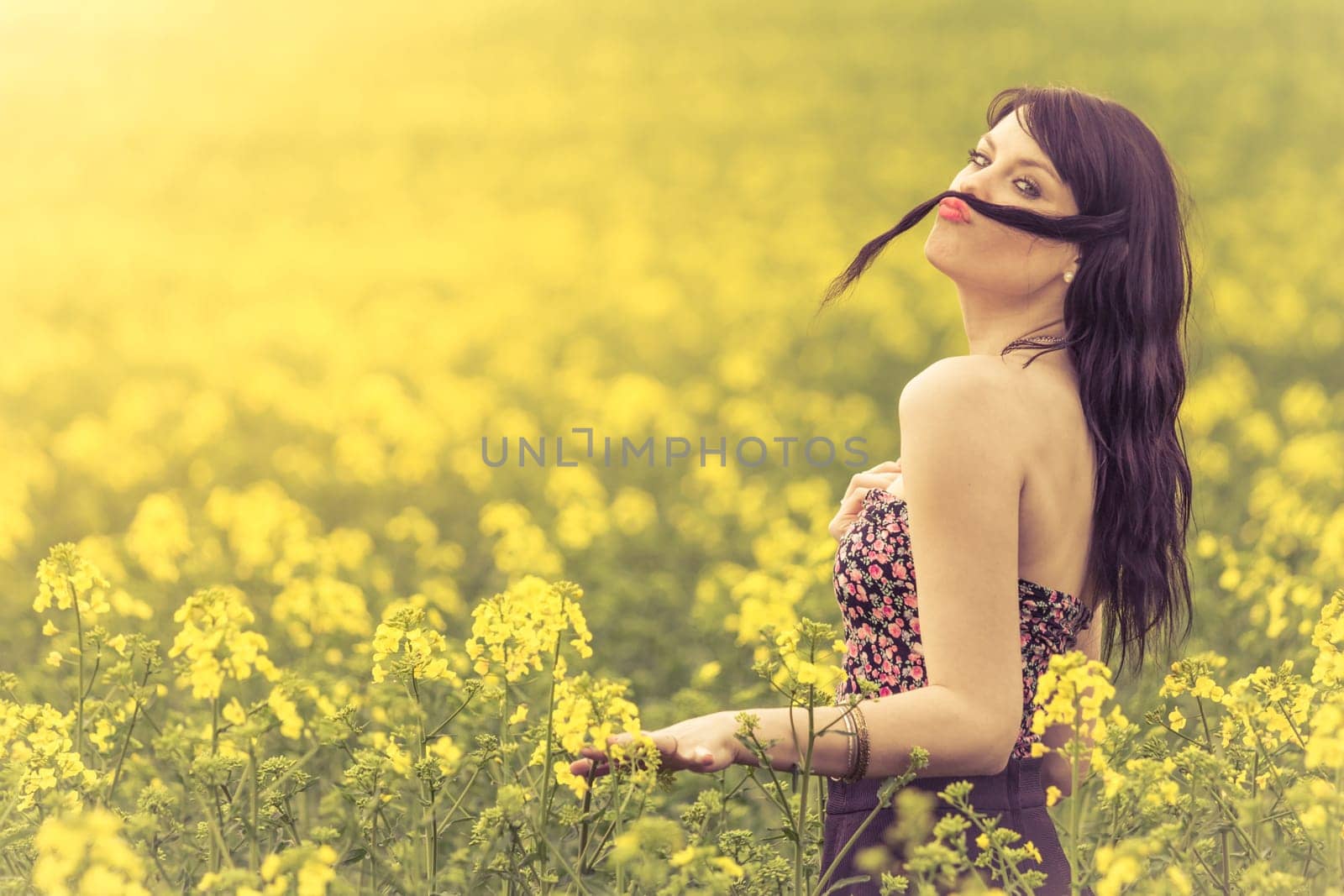 Attractive happy young girl enjoying the warm summer sun and her health in a wide green and yellow meadow. Part of series.